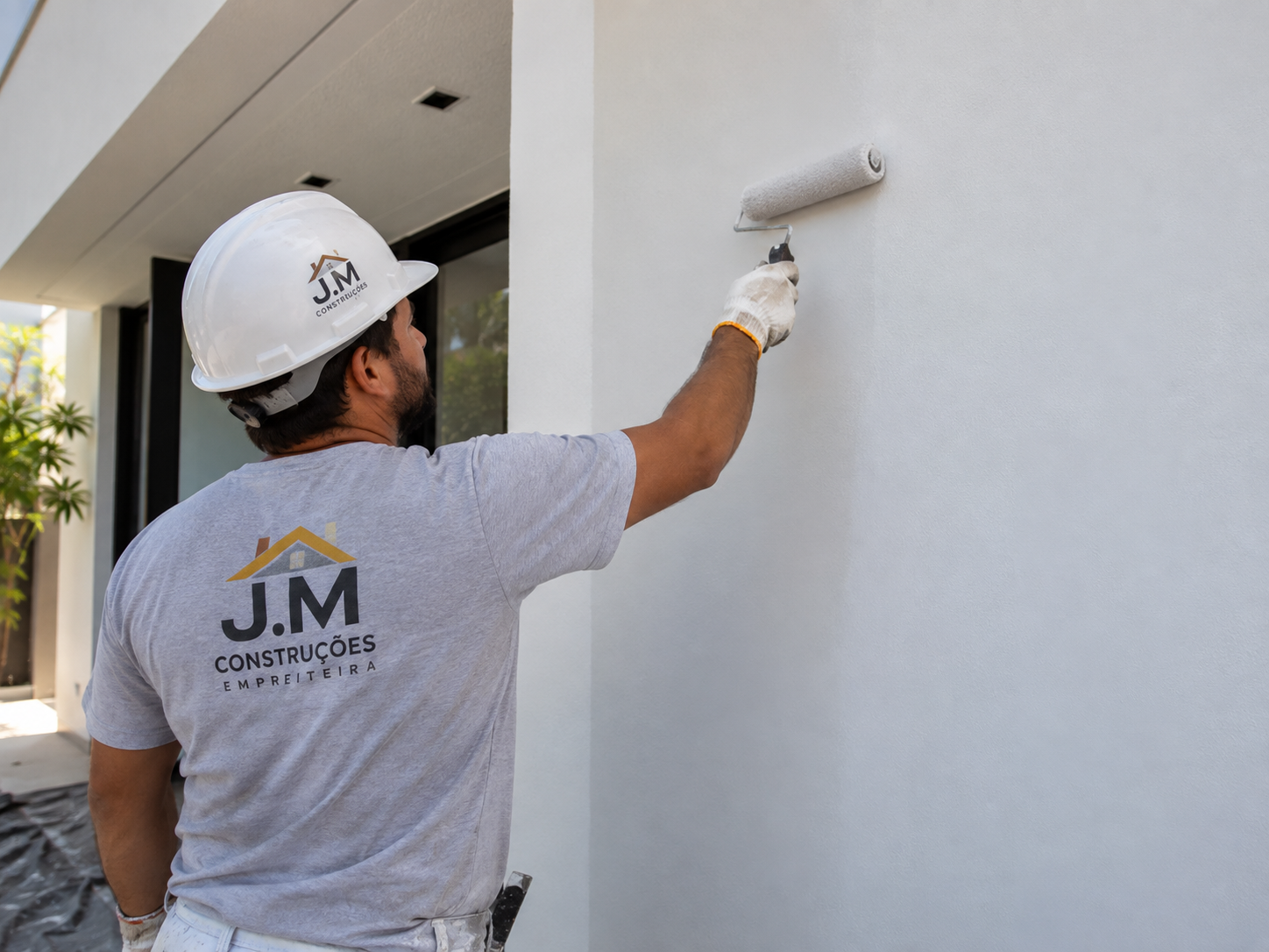 Profissional da J.M Construções aplicando pintura em fachada